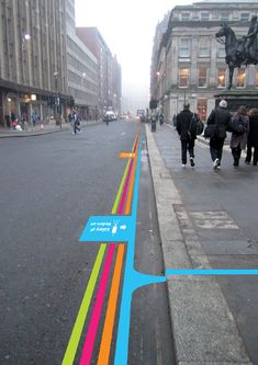 people are walking down the street with colorful lines painted on it