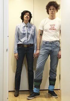 two people standing next to each other in front of a door with their hands on their hips