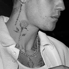 a young man with tattoos on his neck and chest is looking to the side while holding a cell phone