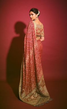 a woman in a red and gold sari standing with her hands on her hips