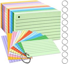 a stack of colored paper with rings and binders next to each other on a white background