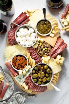 a wooden platter filled with different types of cheeses, meats and fruit