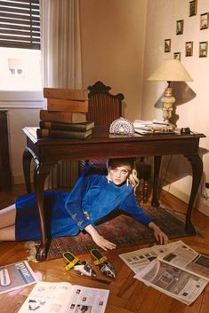 a woman is laying on the floor surrounded by newspapers and other items that are scattered around her