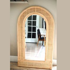 a mirror sitting on top of a hard wood floor next to a chair and table