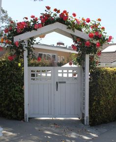 a white gate with flowers growing over it