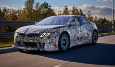 the new bmw 8 series sedan is driving on a road with trees in the background