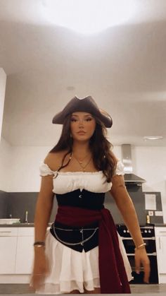 a woman wearing a pirate costume standing in a kitchen