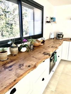 a kitchen counter with pots and pans on it, in front of a window