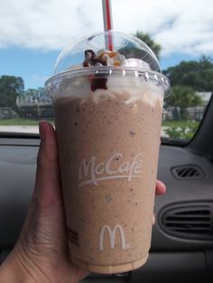 a person holding up a drink in front of a car window with the mcdonald's logo on it