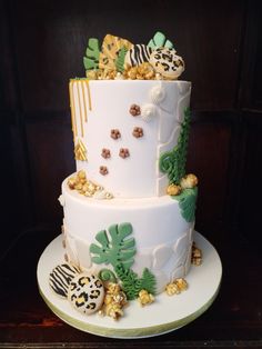 a three tiered cake is decorated with tropical leaves and other edible things on it