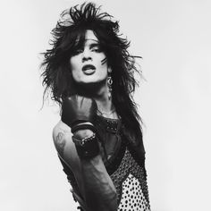 a black and white photo of a woman with her hair blowing in the wind, wearing leather gloves