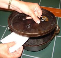 a person holding a piece of paper in front of a pot on top of a table