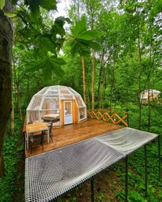 a small house in the woods with a table and chairs on it's deck