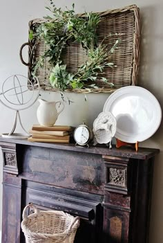 a table topped with plates and vases on top of a wooden mantle next to a basket