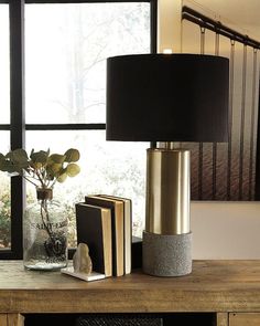 a lamp that is on top of a table next to some books and a vase