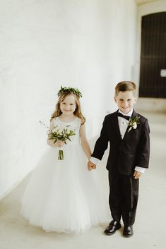 a young boy and girl in formal wear holding hands