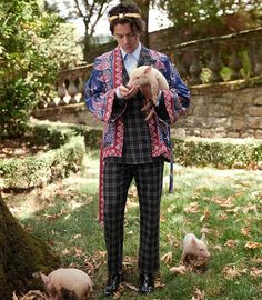 a man standing in the grass holding a lamb next to some small pig's