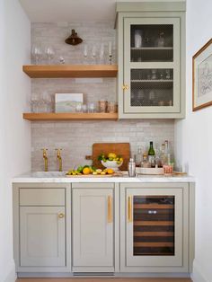 a kitchen with gray cabinets and white counter tops, wine glasses on the shelf above the sink