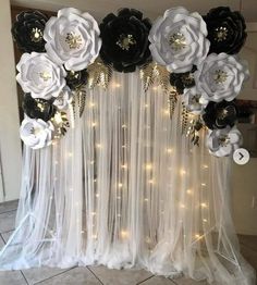 a white and black wedding backdrop with flowers on the side, lights in the background