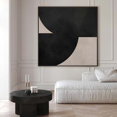 a black and white painting hanging on the wall next to a couch in a living room