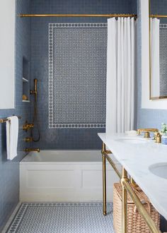 a bathroom with blue tile and gold fixtures in the bathtub, sink, and shower curtain