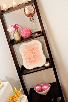 a shelf with candles, plates and bowls on it in front of a white wall