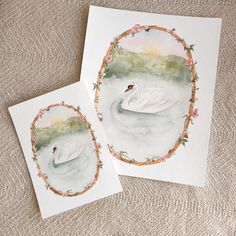 two watercolor paintings of swans in a circle on a white background, one with pink flowers and the other with green leaves