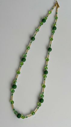 Pretty Green Glass Bead Necklace  The necklace has been made with green glass beads, gold seed beads, green seed beads and dark green carved pattern beads. The necklace has been finished with a gold plated toggle clasp. Green Beaded Chain Jewelry, Green Crystal Necklaces With Colorful Round Beads, Green Necklaces With Gold Beads For Jewelry Making, Green Jade Beaded Necklaces As Gift, Green Beaded Czech Glass Jewelry, Green Czech Glass Beaded Chain Jewelry, Green Czech Glass Jewelry With Beaded Chain, Green Necklaces With Colorful Round Beads, Handmade Adjustable Green Emerald Necklace