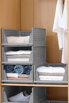 an organized closet with clothes and shoes in grey bins on the bottom shelf, next to a white t - shirt