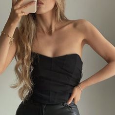 a woman is taking a selfie with her cell phone while wearing a black strapless dress