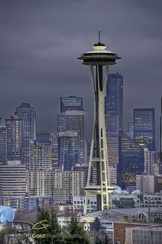 the space needle in seattle, washington state is lit up at night with dark clouds