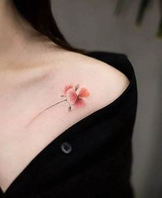 a woman's shoulder with a small flower tattoo on her left side ribcage