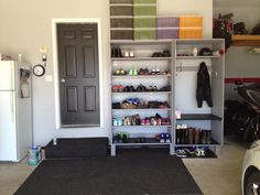 an organized garage with shoes and other items on the shelf next to the door, in front of a motorcycle