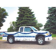 a white truck with blue stripes parked on the side of the road in front of some trees