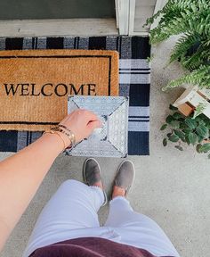 a person standing in front of a welcome mat and doormat with the word welcome on it