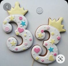 two decorated birthday cookies on top of a white table next to a penny for the number three