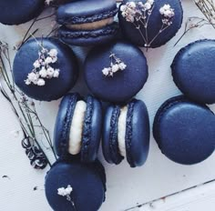 blue macaroons with white flowers on them sitting next to some branches and twigs