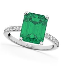 an emerald and diamond ring on a white background