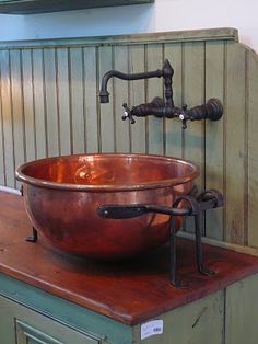 an old fashioned copper bowl sink on top of a wooden counter with faucet