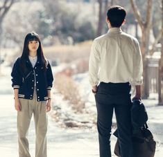 a woman standing next to a man on a sidewalk