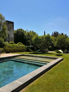 an outdoor swimming pool surrounded by grass and trees