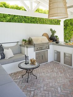 an outdoor kitchen with grill, sink and table in the middle of the patio area