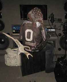 a man sitting on top of a wooden block in front of a monitor and speakers