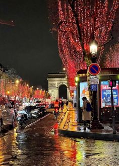 a city street with cars parked on the side and people walking down the sidewalk at night