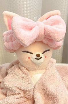 a teddy bear with a pink bow on it's head sitting in a bathrobe