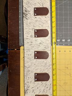 three pieces of leather with holes in them on a table next to a measuring ruler