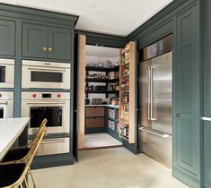 a kitchen with green cabinets and stainless steel appliances in the center, along with an open pantry