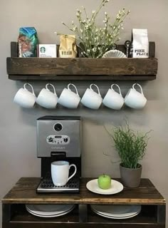 there is a coffee maker and some cups on the shelf next to the potted plant