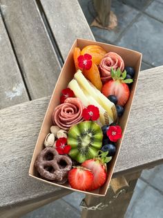 a box filled with assorted fruit on top of a wooden table next to a bench