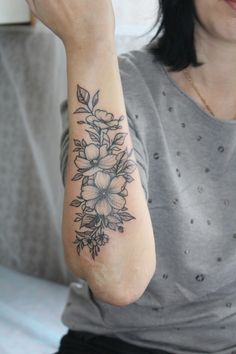 a woman with a flower tattoo on her arm holding a cell phone up to her ear